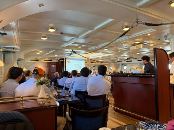 Sessió professional a bord del Clipper Stad Amsterdam amb assistents seguint una ponència en un dels espais interiors del vaixell.